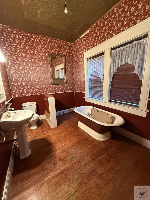 bathroom featuring toilet, hardwood / wood-style flooring, and a bath