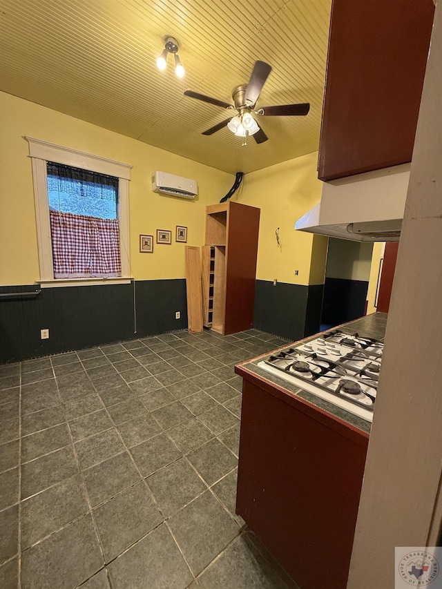 kitchen with wainscoting, wooden ceiling, an AC wall unit, and a ceiling fan