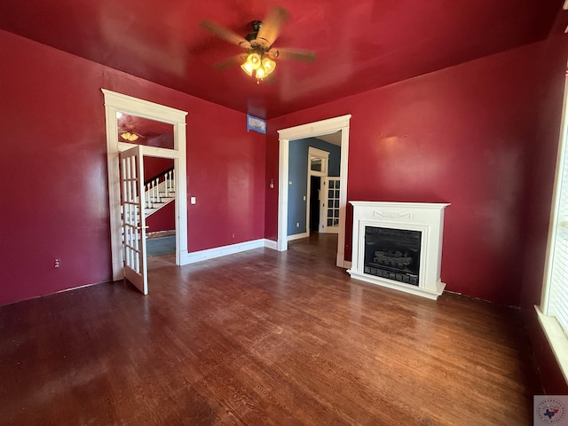 unfurnished living room featuring a fireplace, stairs, a ceiling fan, and wood finished floors