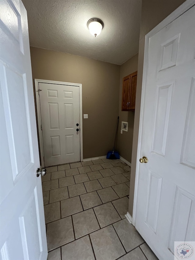washroom featuring hookup for a washing machine, cabinets, a textured ceiling, and light tile patterned floors