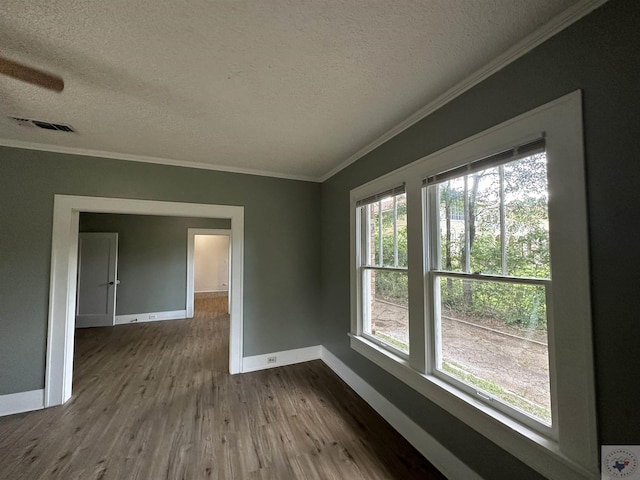 empty room featuring wood-type flooring, a textured ceiling, and ornamental molding