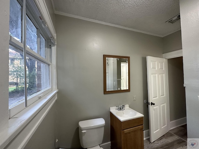 bathroom featuring hardwood / wood-style flooring, toilet, a textured ceiling, vanity, and ornamental molding