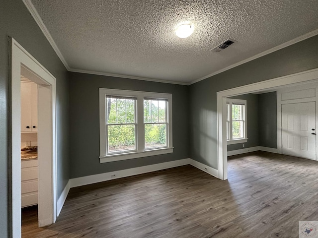 empty room featuring ornamental molding, dark wood-type flooring, and a textured ceiling