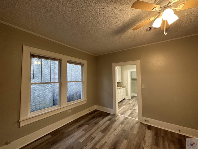 spare room featuring hardwood / wood-style floors, a textured ceiling, and ornamental molding