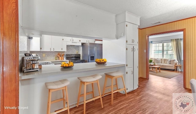 1208 Colorado St, Texarkana, TX 75503 - kitchen featuring black electric range oven, stainless steel refrigerator with ice dispenser, under cabinet range hood, ornamental molding, and tasteful backsplash
