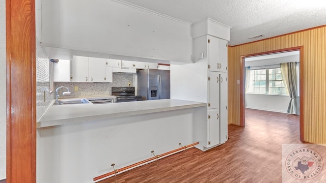 kitchen featuring stainless steel refrigerator with ice dispenser, black electric range oven, sink, white cabinetry, and ornamental molding