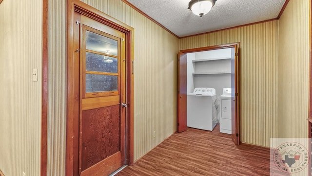 hallway with ornamental molding, washing machine and clothes dryer, hardwood / wood-style floors, and a textured ceiling