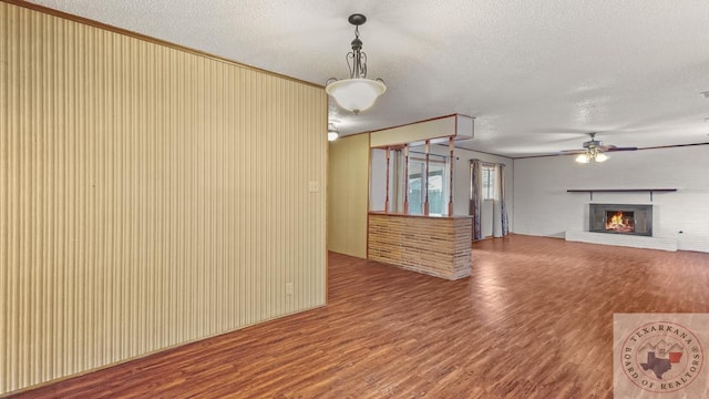 unfurnished living room featuring ceiling fan, crown molding, a textured ceiling, and wood-type flooring