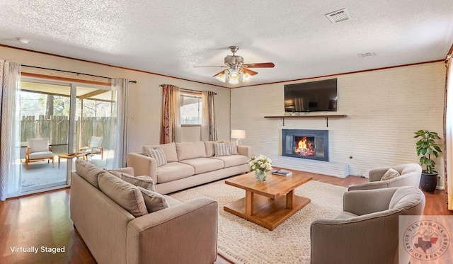 1208 Colorado St, Texarkana, TX 75503 - living area featuring wood finished floors, a textured ceiling, plenty of natural light, a glass covered fireplace, and a ceiling fan