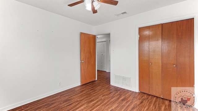 unfurnished bedroom with a closet, a textured ceiling, dark hardwood / wood-style floors, and ceiling fan