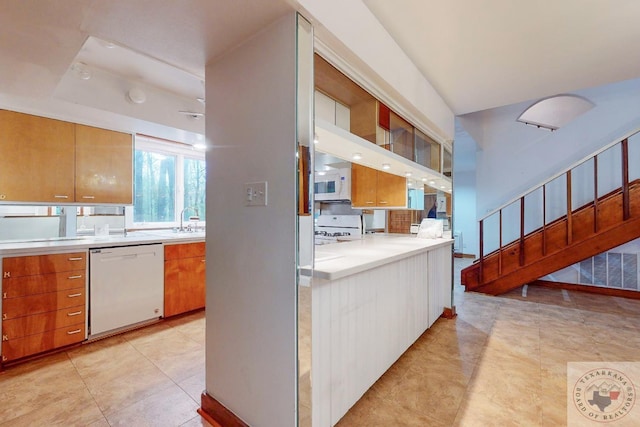 kitchen featuring sink, light tile patterned flooring, white appliances, and a tray ceiling