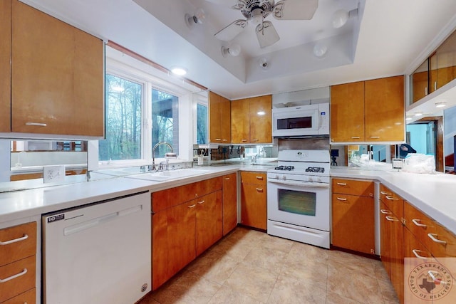 kitchen with sink, ceiling fan, white appliances, and a raised ceiling