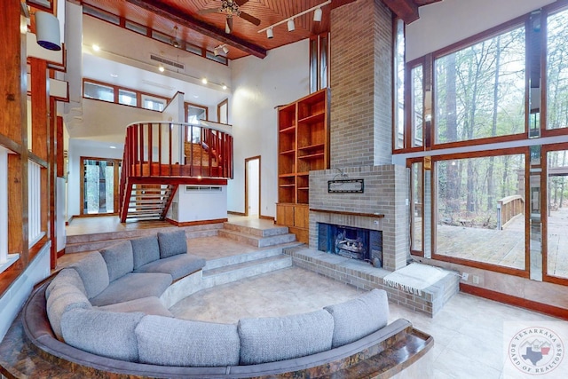 living room featuring wood ceiling, a towering ceiling, a wealth of natural light, and a fireplace