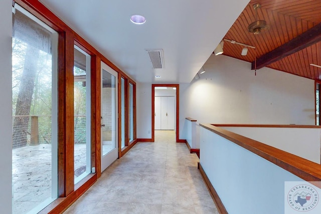 corridor featuring beamed ceiling, a healthy amount of sunlight, and wooden ceiling