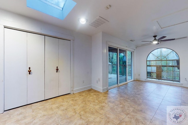 unfurnished bedroom with ceiling fan, a skylight, and access to outside