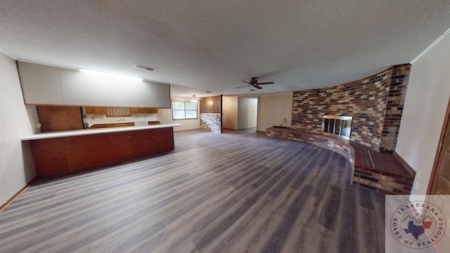 unfurnished living room featuring ceiling fan, a fireplace, a textured ceiling, and wood-type flooring