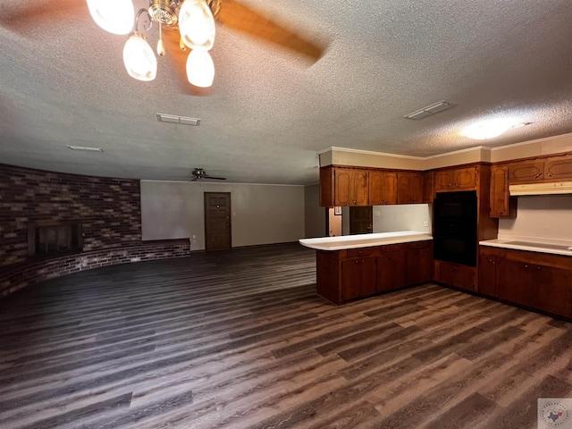 kitchen featuring a textured ceiling, stovetop, dark hardwood / wood-style floors, kitchen peninsula, and ceiling fan