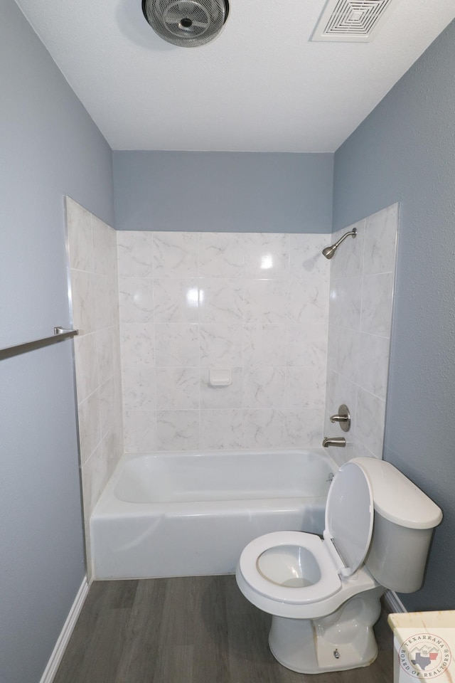 bathroom featuring hardwood / wood-style floors, toilet, and tiled shower / bath combo