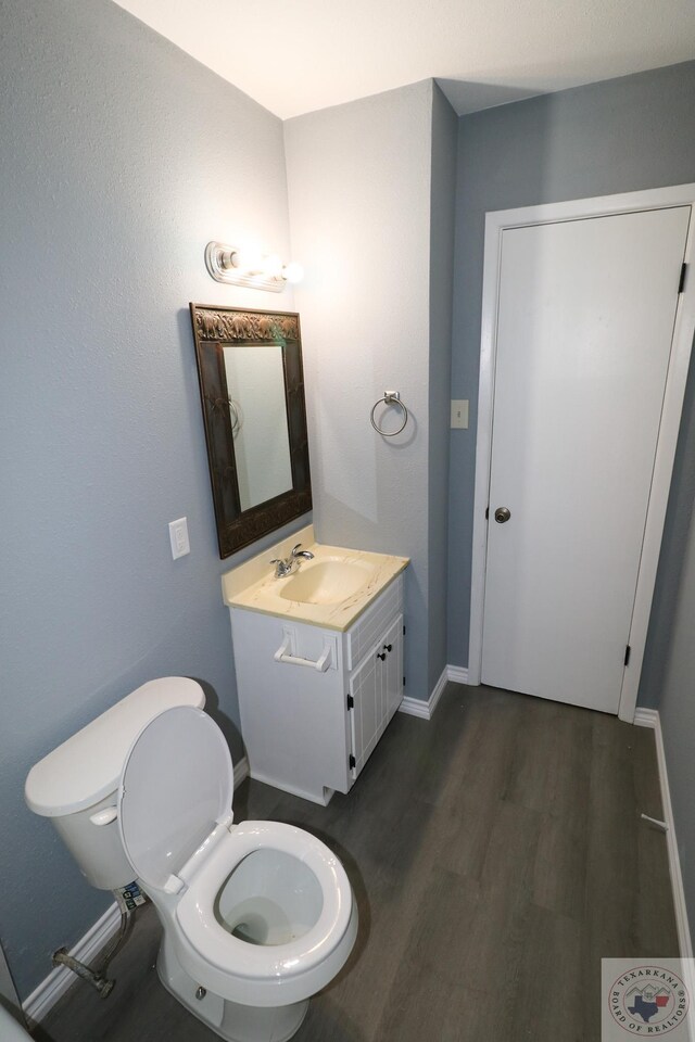 bathroom with hardwood / wood-style floors, toilet, and vanity