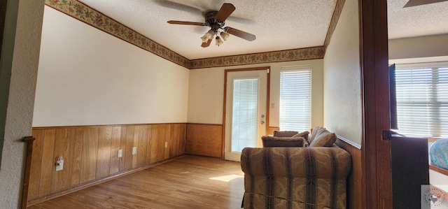 sitting room with a healthy amount of sunlight, a textured ceiling, light hardwood / wood-style flooring, and ceiling fan