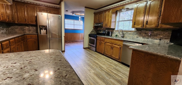 kitchen with light stone countertops, a textured ceiling, appliances with stainless steel finishes, sink, and ornamental molding