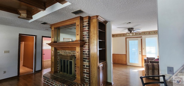 kitchen with ceiling fan, a brick fireplace, a textured ceiling, and wood-type flooring