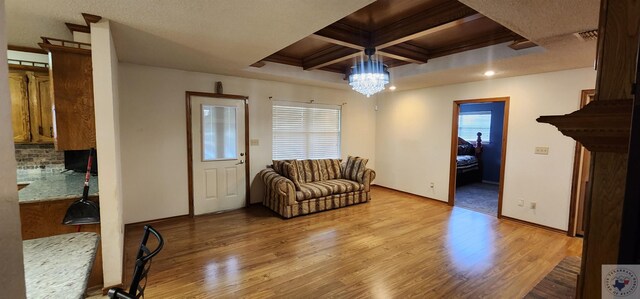 interior space with coffered ceiling, beam ceiling, light hardwood / wood-style floors, and an inviting chandelier