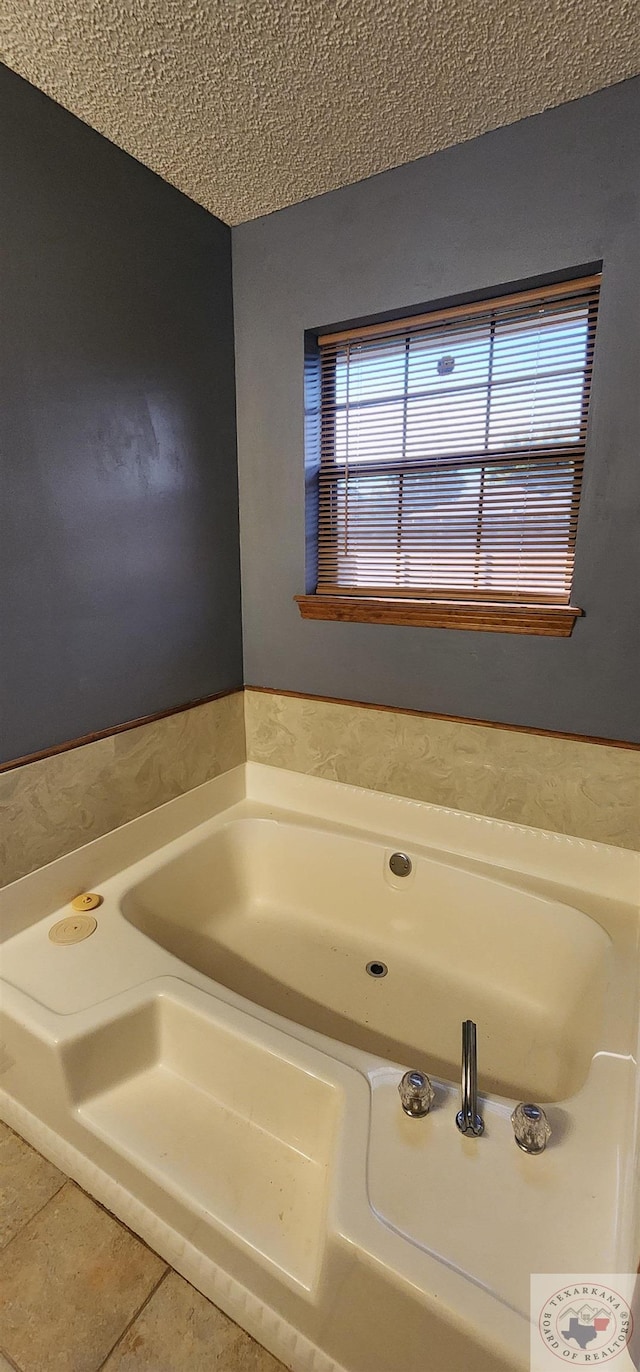 bathroom with a washtub, a textured ceiling, and tile patterned flooring