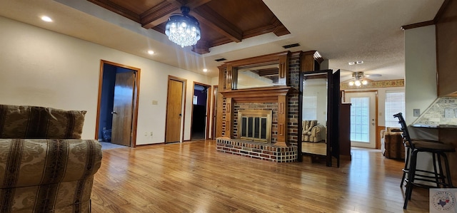 living room with coffered ceiling, beamed ceiling, light hardwood / wood-style floors, and a fireplace