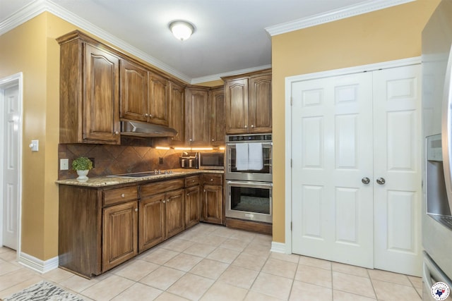 7 Brittan Pl, Texarkana, TX 75503 - kitchen with appliances with stainless steel finishes, under cabinet range hood, decorative backsplash, light tile patterned floors, and light stone counters