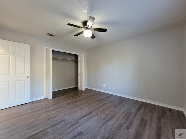 unfurnished bedroom featuring ceiling fan, dark wood-type flooring, a textured ceiling, and a closet