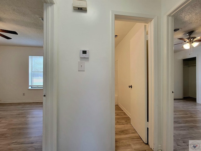 hall featuring a textured ceiling and hardwood / wood-style floors