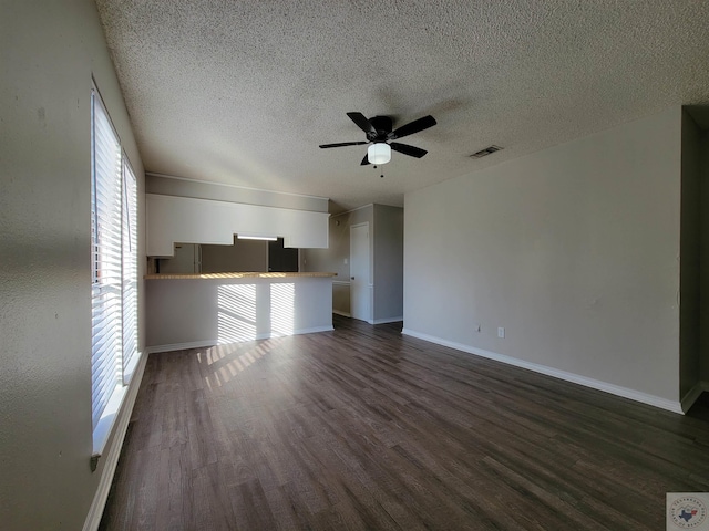 unfurnished living room featuring ceiling fan, a textured ceiling, and dark hardwood / wood-style floors