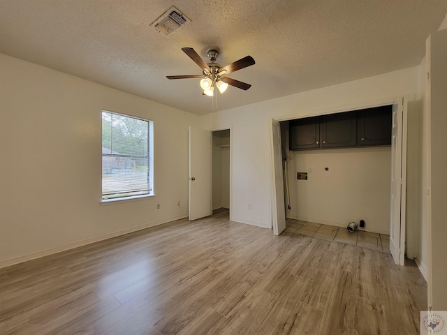 unfurnished bedroom with a textured ceiling, light hardwood / wood-style flooring, a closet, and ceiling fan