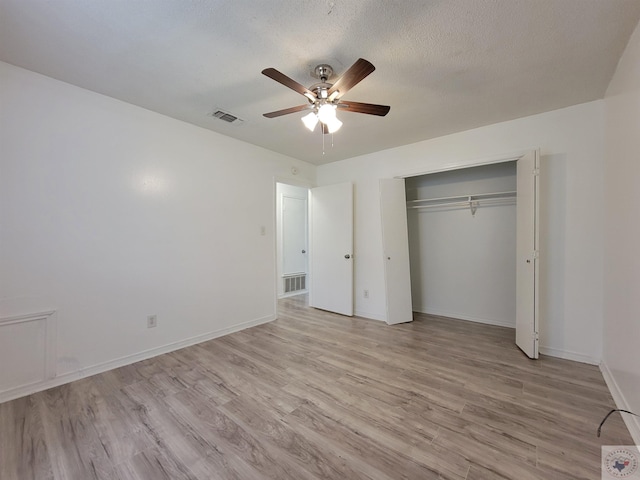 unfurnished bedroom with a textured ceiling, light hardwood / wood-style flooring, a closet, and ceiling fan