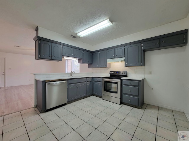 kitchen with a textured ceiling, gray cabinetry, light tile patterned floors, and stainless steel appliances