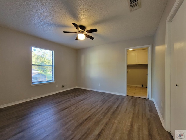 spare room with ceiling fan, a textured ceiling, and dark hardwood / wood-style floors