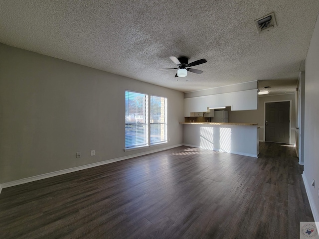 unfurnished living room with ceiling fan, a textured ceiling, and dark hardwood / wood-style flooring