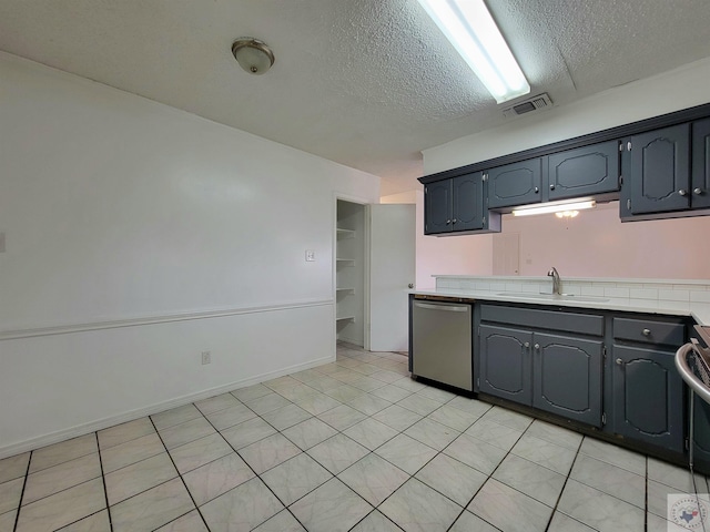 kitchen featuring sink, a textured ceiling, light tile patterned floors, and stainless steel appliances