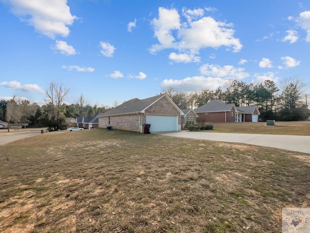 view of home's exterior with concrete driveway, brick siding, a yard, and an attached garage