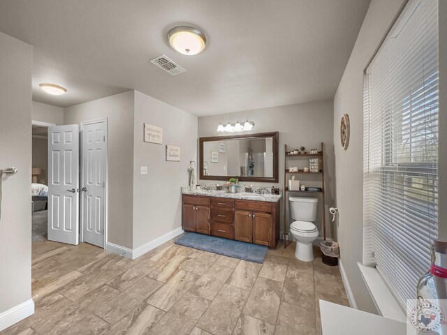 full bathroom featuring toilet, a sink, visible vents, baseboards, and double vanity