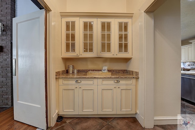 bar featuring baseboards, stainless steel dishwasher, and dark tile patterned flooring