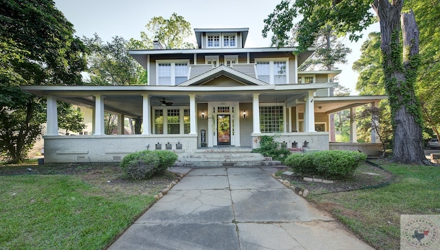 view of front facade with a ceiling fan, a front yard, brick siding, and a porch