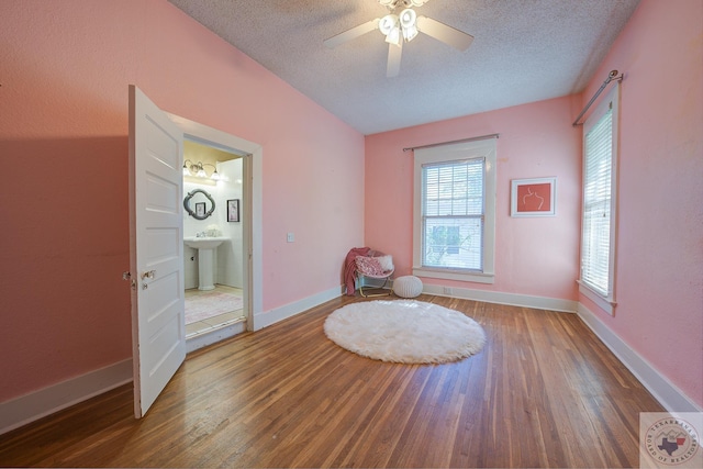 living area with a textured ceiling, baseboards, and wood finished floors