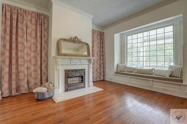 unfurnished living room with ornamental molding, a fireplace, wood finished floors, and visible vents