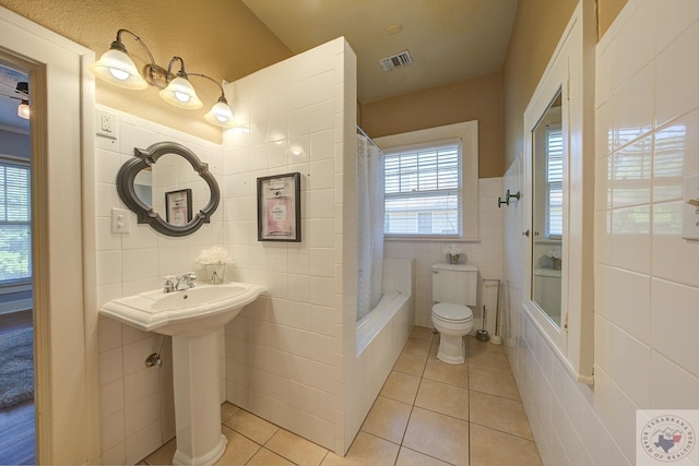 full bathroom with visible vents, toilet, tile patterned flooring, shower / bath combination with curtain, and tile walls