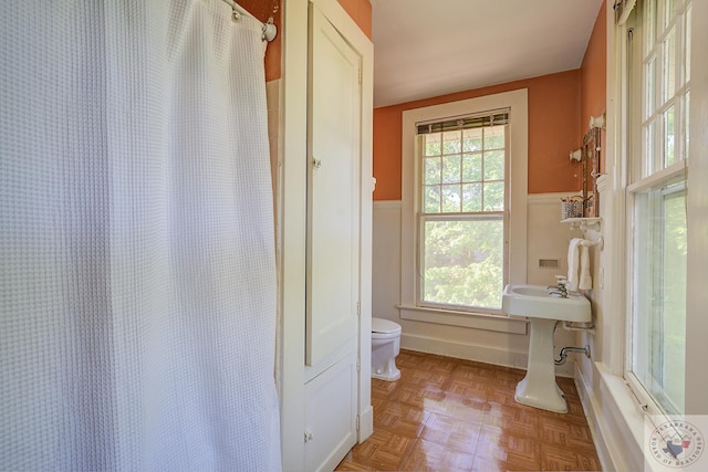 bathroom featuring toilet, a shower with curtain, and wainscoting