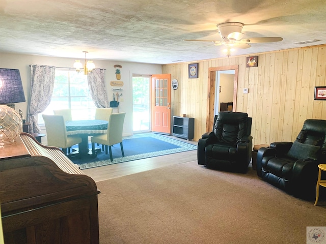 carpeted living room with an inviting chandelier and wooden walls