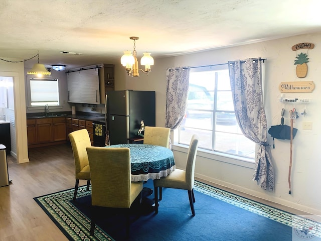 dining area with sink, a chandelier, and light wood-type flooring