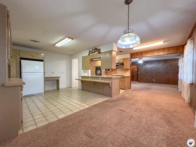 kitchen with wooden walls, visible vents, freestanding refrigerator, a peninsula, and a textured ceiling